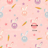 a repeating pattern of smiling rabbit faces and carrots against a pink background, with the size of the rabbit faces being 2.5 cm in size.