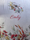 a close-up view of a white fabric with a floral design and the name "Emilly" written in red cursive text.