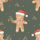 a repeating pattern of gingerbread men wearing Santa hats and scarves, holding pine branches and Christmas ornaments against a dark green background with white snowflakes scattered throughout.