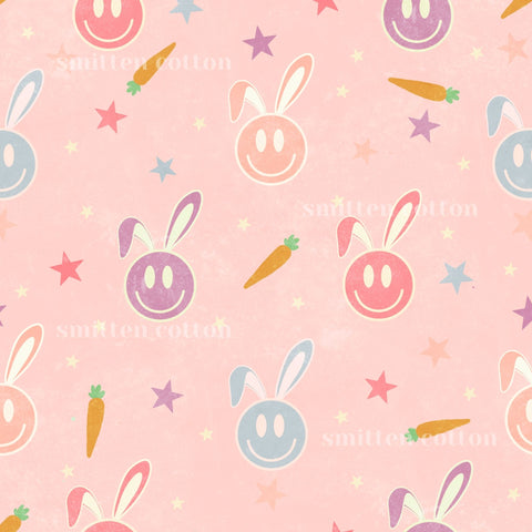 a repeating pattern of smiling bunny faces and carrots against a pink background.