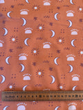 a fabric with a repeating pattern of sun and moon silhouettes, along with some decorative elements such as swirls and dots. A ruler is placed next to the fabric, likely for measuring purposes.