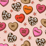 a pattern of heart-shaped candies with various sayings and designs, such as "Honey", "Howdy", "Yall", "Hi", "COW GIRL", and "Honey", along with stars scattered throughout the background.