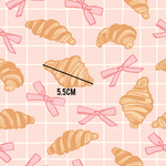 a pattern of croissants with bows on a pink background