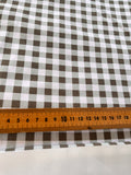 a close-up view of a ruler placed next to a fabric with a gingham pattern.