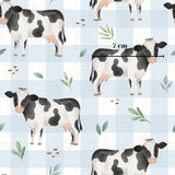 a repeating pattern of black and white cows on a blue and white checkered background.