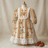 A dress with a gingham pattern and lace trim, featuring cow and flower designs, displayed on a mannequin.