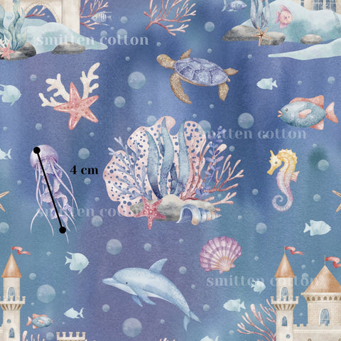 The image is a watercolor painting depicting various marine life, including a turtle, starfish, jellyfish, and a castle, all set against a blue background with bubbles.