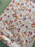 a white fabric with a repeating floral pattern of red and green flowers and leaves.
