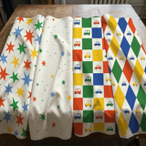 four fabric pieces with different patterns and designs, including stars, cars, and checkered patterns.