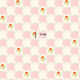 a pattern of pink and white squares with small orange flowers scattered throughout.